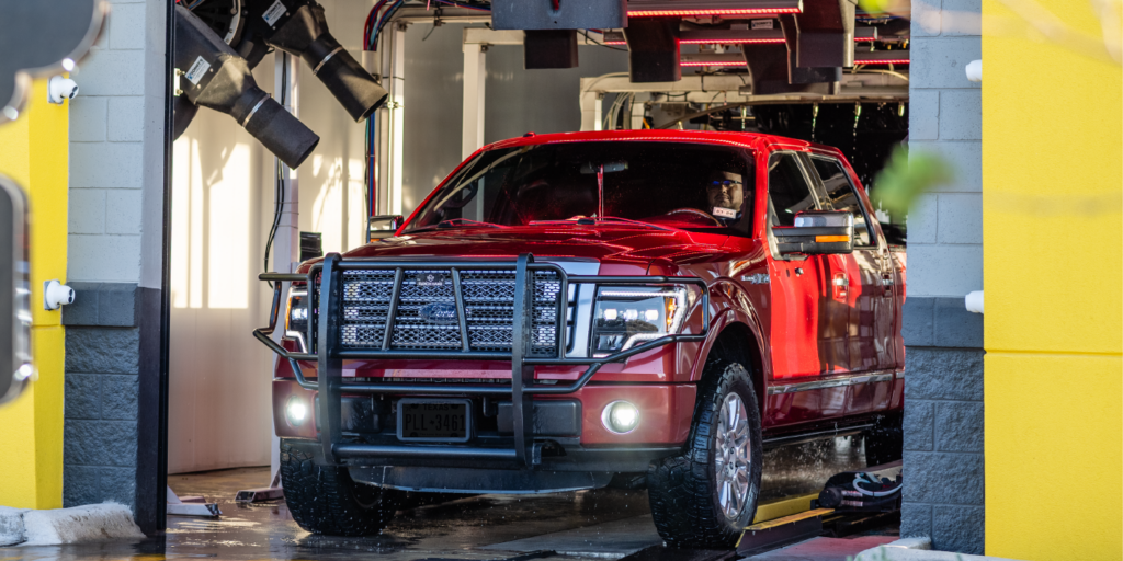 Red truck driving thru a quick quack car wash